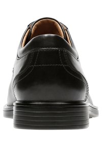 Schwarze Leder Schuhe mit glatter Oberfläche, runder Zehenform und gesteppten Details, ausgestattet mit einer niedrigen, strukturierten schwarzen Gummisohle.