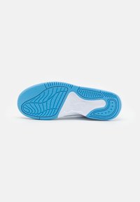 Semelle d'une chaussure Nike Air blanche et bleu clair avec des motifs de grip texturés, présentée sur un fond uni gris clair.