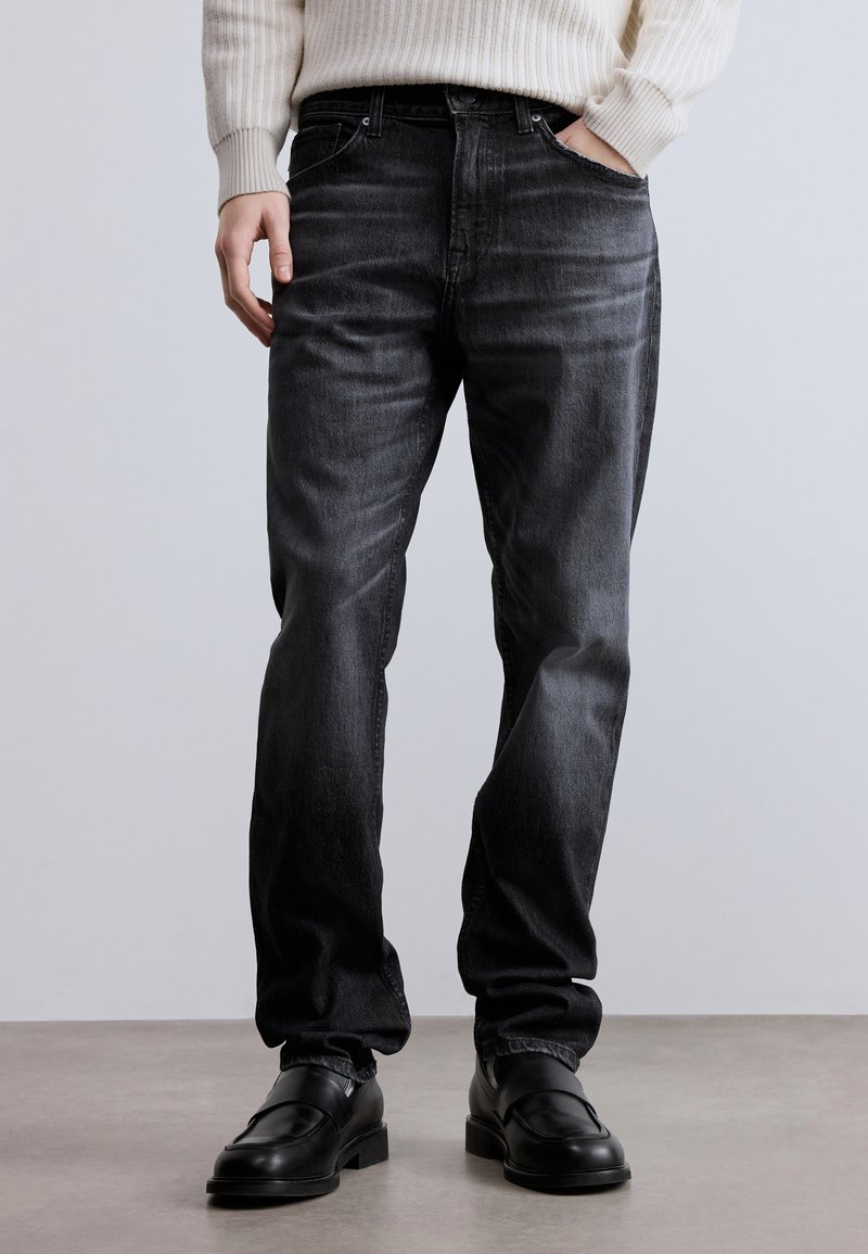 Fekete, egyenes szabású farmernadrág finom fakulással, öt zsebbel, övbújtatókkal és klasszikus gombsorral.