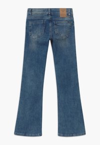 Blue denim flared jeans featuring a smooth texture, two back pockets, and a tan branded patch on the waistband.