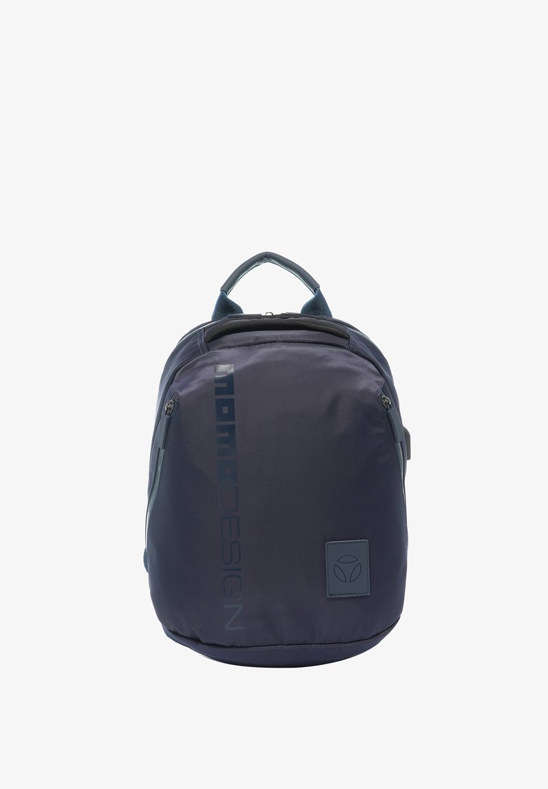Sac à dos compact bleu foncé avec poignée supérieure, poches zippées frontales, nom de marque vertical, et petite étiquette carrée avec logo en bas à droite.