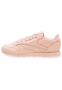 Ljusrosa Reebok lädersneakers med vit sula, snörning och varumärkning på sidan, tungan och hälen, visad från vänster sida.