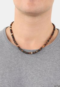 Perlenhalskette mit schwarz, braun und cremefarbenen Perlen in verschiedenen Größen, die in einem einfachen, kreisförmigen Design aufgezogen sind.