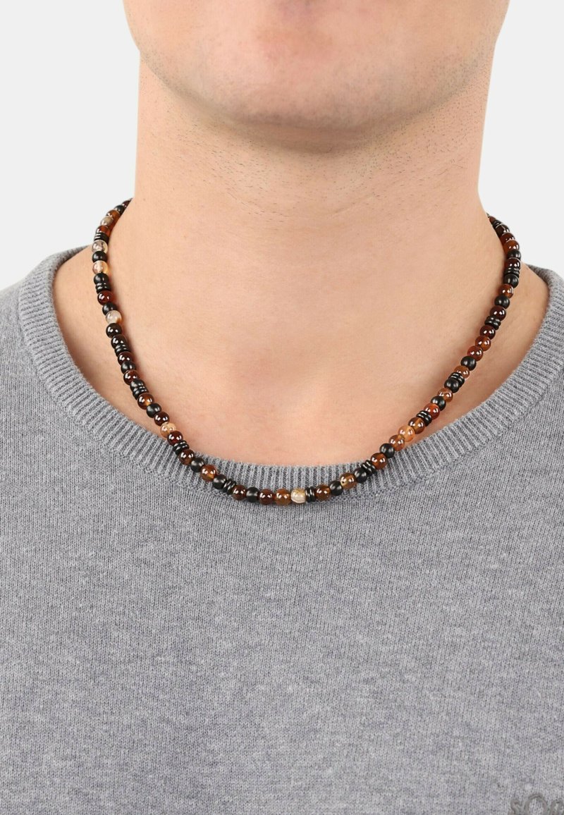 Perlenhalskette mit schwarz, braun und cremefarbenen Perlen in verschiedenen Größen, die in einem einfachen, kreisförmigen Design aufgezogen sind.