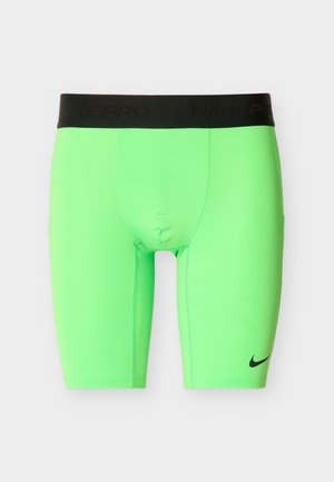 Neonowo zielone kompresyjne spodenki Nike Pro z czarnym paskiem w talii i małym czarnym logo Nike na lewej nodze.