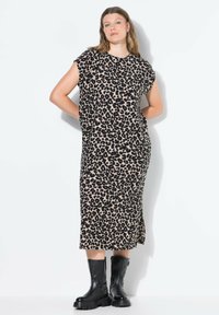 Rento leopardikuosiset ilmanhihaiset mekko beige ja mustana, jossa on rento leikkaus ja sivuhalkiot, yhdistettynä mustiin nilkkasaappaisiin.