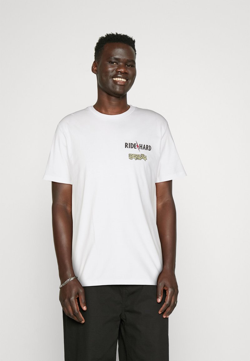 Camiseta de algodón blanca con mangas cortas, que presenta un gráfico de "RIDE HARD" y un diseño de rayo en negro y amarillo.