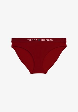 Fronhas de biquíni de algodão vermelho com um design sólido e uma cintura marcada com "TOMMY HILFIGER" em texto branco. Textura suave.