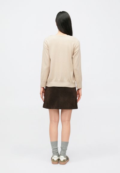 Bēšs adīts džemperis, brūna zamšādas svārki, pelēkas zeķes, zaļi balti sporta apavi. Vienkāršs dizains, vidēja biezuma, ikdienas piegriezums. Skats no aizmugures.