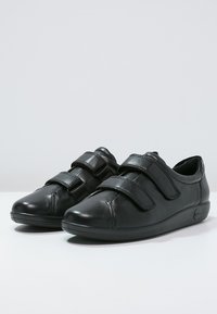 Scarpe in pelle nera con due cinturini regolabili in Velcro, design della punta arrotondata, cuciture sottili, suola in gomma a profilo ridotto e logo laterale.