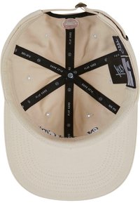 Intérieur d'une casquette beige avec une texture de tissu doux, dotée de sangles noires marquées "PLAY HARD", de trous de ventilation et d'un bouton-pression central.