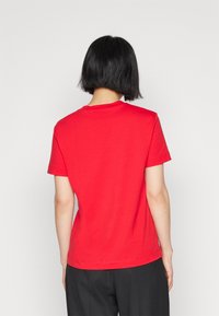 Red cotton t-shirt with short sleeves, round neckline, and a regular fit. The fabric appears soft with a smooth texture and no visible patterns.