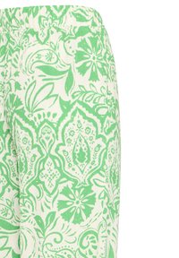 Pantalon blanc avec une ceinture élastique présentant un motif complexe de fleurs vertes et de paisley sur l'ensemble du tissu.