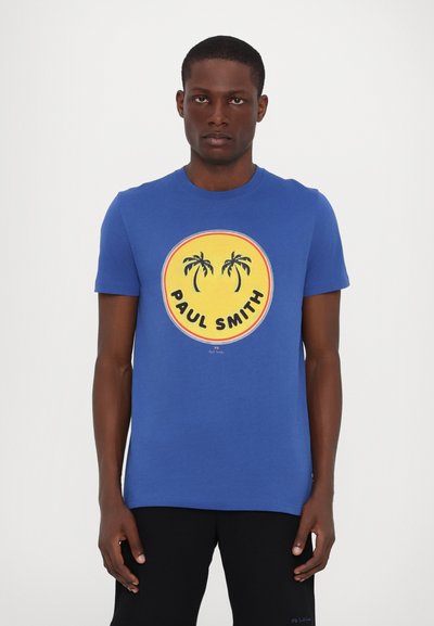 Tricou din bumbac albastru, cu un grafic rotund galben ce prezintă palmieri și textul "PAUL SMITH". Mâneci scurte și guler rotund.