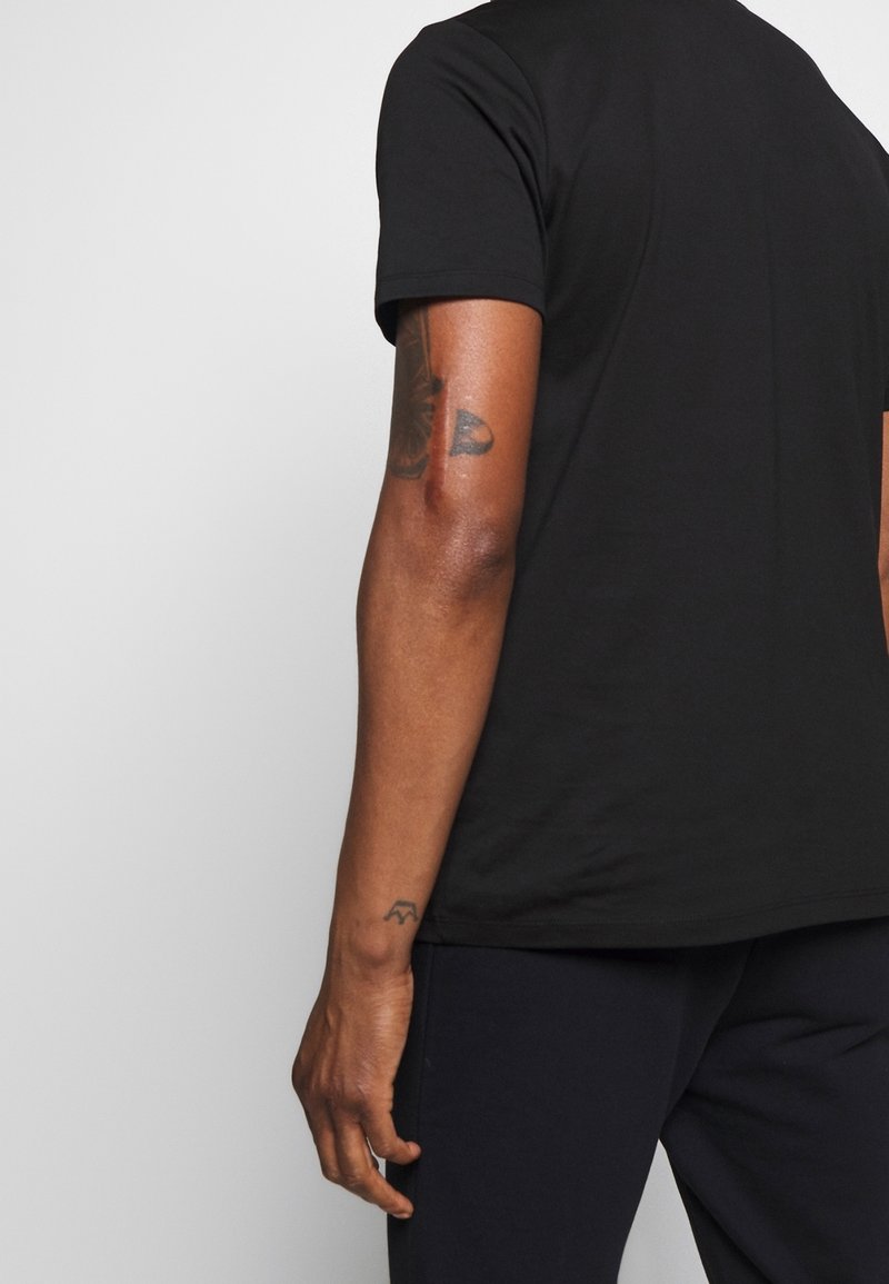 T-shirt noir à manches courtes, en coton doux. Coupe décontractée avec un col rond et un design minimaliste. Texture lisse, sans motifs visibles.
