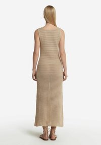 Beige, virkat maxi-klänning med rundad halsringning och ärmlös design; har en rak silhuett och ett öppet vävda textur.