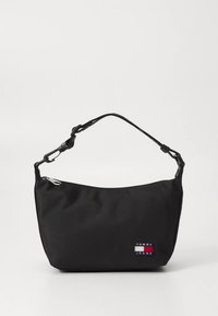 Bolso de hombro de tela negra con parte superior curva, correa ajustable, herrajes plateados y un pequeño parche con el logo de Tommy Jeans en el lateral.