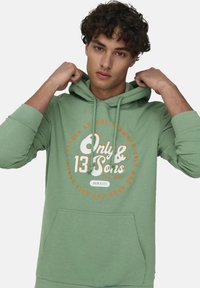 Sudadera verde de mezcla de algodón, con un bolsillo tipo canguro, cordones y un gráfico circular del logo "Only & Sons" en el frente.