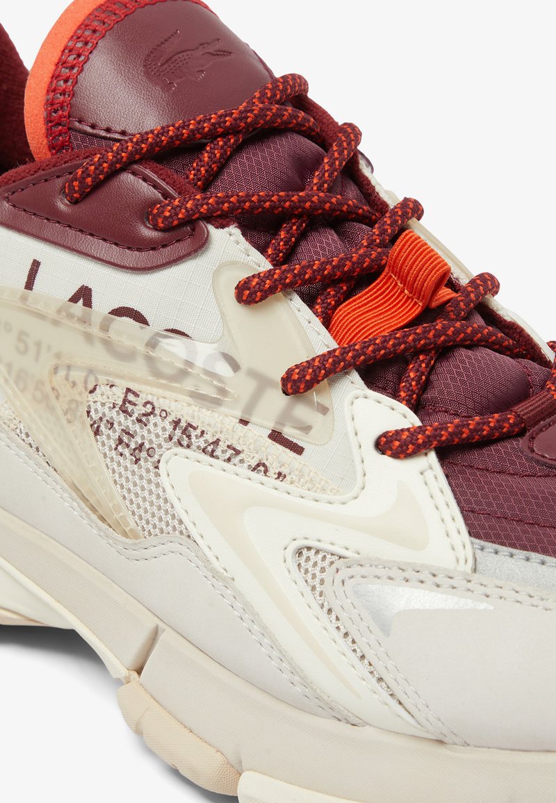 Sneakers Lacoste in pelle color bordeaux e crema con accenti in rete, dotate di lacci texture e marchio sul lato.