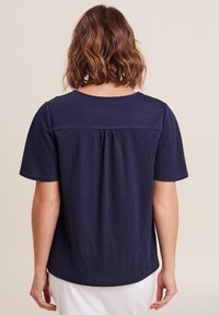 T-shirt a maniche corte di colore blu navy con scollatura rotonda, dotato di un dettaglio sul retro e di pieghe sottili per una vestibilità comoda. Tessuto liscio.