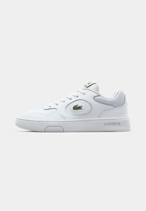 Witte sneaker met een synthetisch bovenwerk, ronde teen en perforaties. Bevat een groen geborduurd logo, platte veters en een gestructureerde zool.