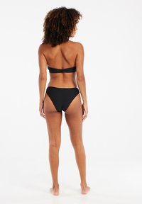 Crni bikini sastoji se od bandeau gornjeg dijela s kopčanjem na kuku i gaćica visokog struka sa teksturiranim cik-cak uzorkom.