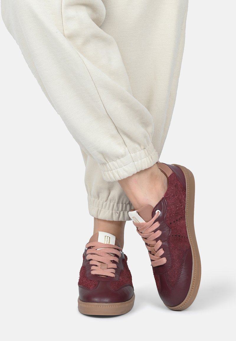 Burgunderfarbene Sneaker aus strukturiertem Stoff und glatten Lederakzenten. Mit beigen Schnürsenkeln und einer Gummisohle mit einem dezenten Muster.