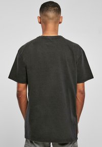 Black cotton t-shirt with short sleeves, crew neck, and a relaxed fit. Features a simple, solid design with casual stitching details.