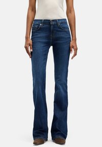 Bootcutjeans i mörk denim med en mjuk struktur och en figurnära midja. Har kontrasterande sömmar och femficksdesign.