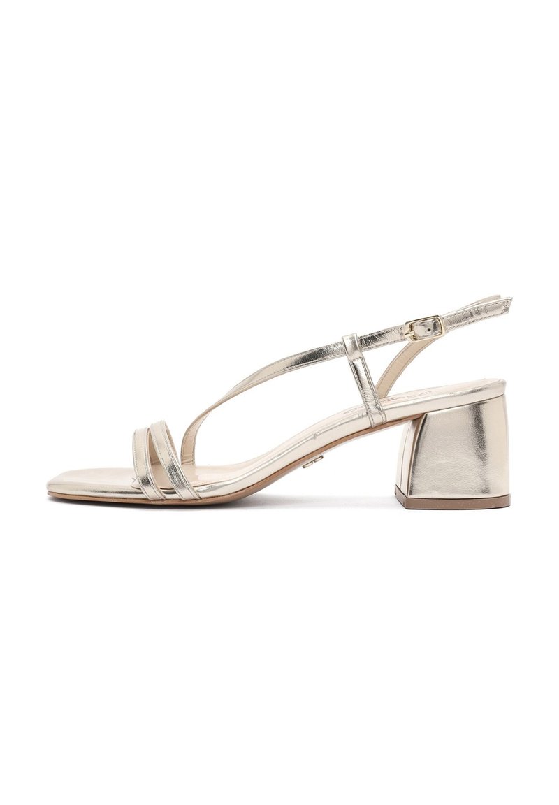 Sandales à talons en or métallique avec un talon bloc, une bride de cheville ajustable et plusieurs bandoulières pour un maintien sécurisé. Texture lisse et brillante.