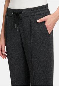 Dunkelgraue Jogginghosen aus strukturiertem Stoff, mit einem Kordelzug an der Taille, Seitentaschen und abgesteppten Details entlang der Beine.