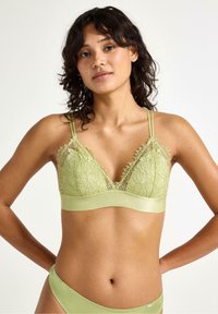 Bralette verde in pizzo con spalline regolabili, motivo floreale e sottobanda in satin. Il tessuto morbido e i dettagli delicati valorizzano il design.
