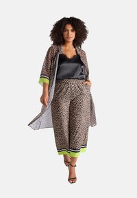 Pantaloni cropped con stampa leopardata e vestibilità ampia, abbinati a un top in satin nero e a un kimono leggero e decorato con accenti neon.
