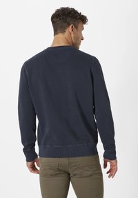 Marineblaue Sweatshirt mit langen Ärmeln, Rundhalsausschnitt und geripptem Saum. Der Stoff wirkt glatt mit minimalen Nähdetails auf der Rückseite.