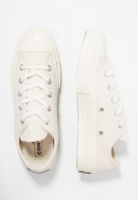Sneakers in tela chiara con punta arrotondata, lacci bianchi, occhielli argentati e suola in gomma testurizzata.