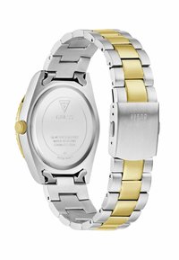 Montre en acier inoxydable avec un bracelet bi-matière ; maillons argent et or ; boîtier rond avec une couronne jaune ; fond gravé indiquant l'étanchéité.