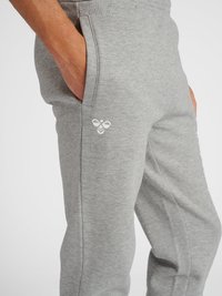 Grijze sweatpants gemaakt van zachte, textuurstof, met een zijzak en een wit logo-accent op het onderbeen.