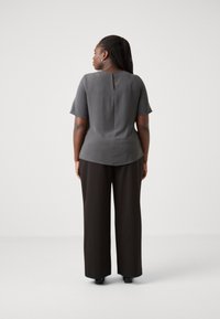 Gray short-sleeve top with a back keyhole detail, paired with black wide-leg trousers. Smooth texture, fitted shape, casual design.