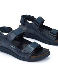 Sandalias de cuero azul oscuro con correas ajustables, plantilla texturizada y suela de goma moteada. Diseño ligero, adecuado para uso casual.