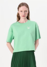 Grønn bomull T-skjorte med korte ermer, med en cropped design og brodert logo på brystet. Glatt tekstur, avslappet passform.