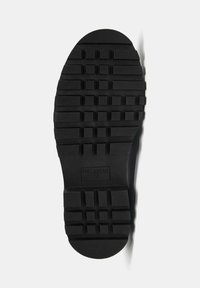 Sort gummisål til sko med tekstureret slidmønster. Rundet tå og flad kant. Prægning "PULL&BEAR 42" på siden.