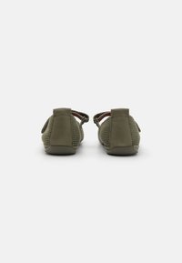 Zapatos de tela de color verde oliva sin cordones, confeccionados con materiales de malla y ante, con puntera redondeada y correas elásticas en el talón para un ajuste seguro.