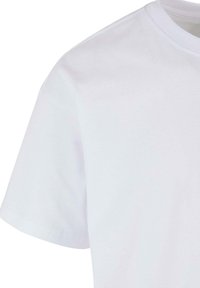 Fehér pamut póló rövidujjal, kerek nyakkal, sima textúrával, és látható minták vagy kiegészítők nélkül. Klasszikus szabású dizájn.