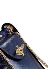 Donkerblauwe leren handtas met een gouden bij-embleem, kettingriem en een gladde textuur; voorzien van een klepsluiting en een gepolijste afwerking.