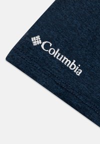 Mørkeblått stoff med en teksturert veving. Har en hvit "Columbia"-logo og en tilstøtende grafikk. Sømdetaljer synlige langs kanten.