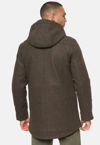Palton maro din lână cu glugă, croială dreaptă și cusături vizibile. Material texturat cu un aspect cald, destinat purtării în aer liber.