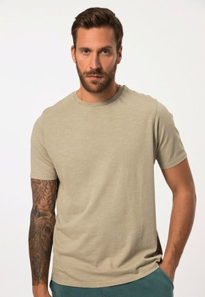 Helle khaki Kurzarm-T-Shirt mit Rundhalsausschnitt, aus weichem Stoff. Das Modell hat sichtbare Tätowierungen auf seinem Arm.