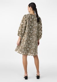 Robe en dentelle florale marron avec des manches bouffantes et un col rond. Présente un motif transparent et une coupe décontractée, atteignant le mi-thigh.