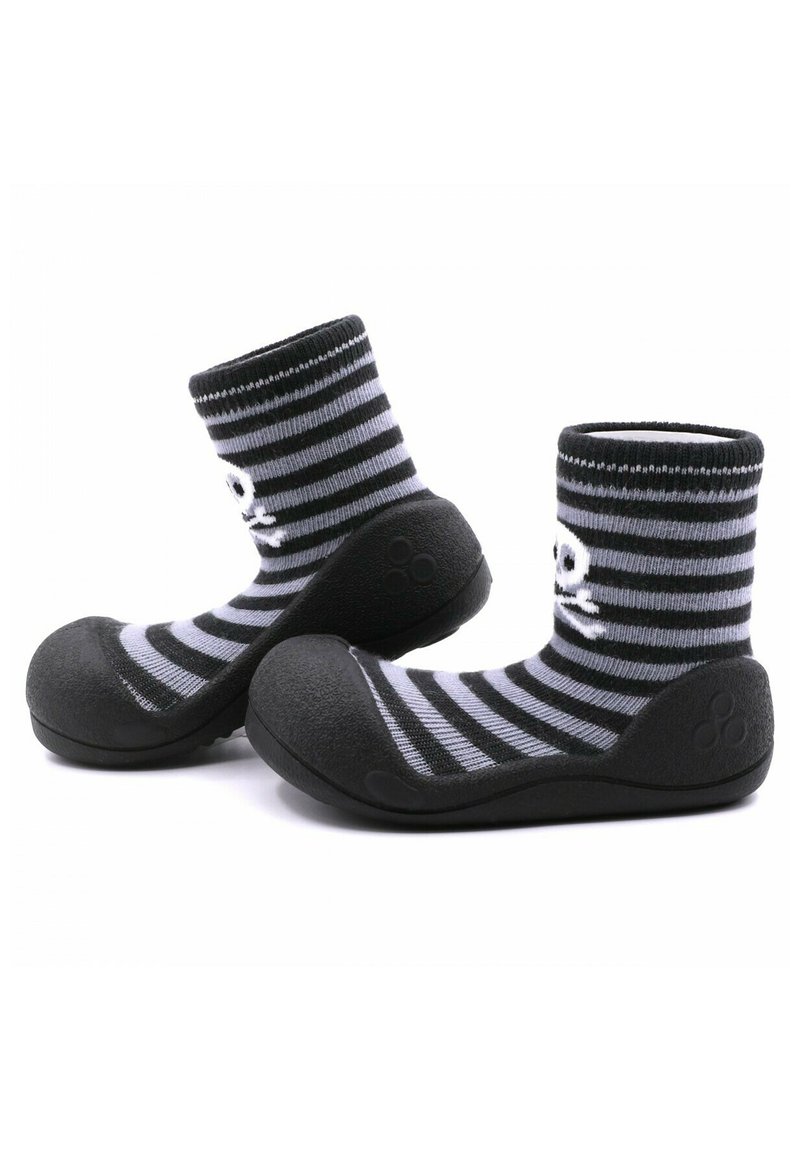 Calcetines a rayas en negro y gris con suela de goma. La parte superior es de tela de punto, y la puntera presenta un acabado redondeado y texturizado.