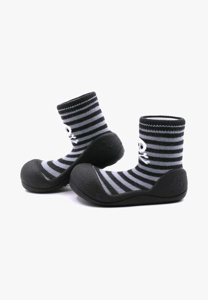 Calcetines a rayas en negro y gris con suela de goma. La parte superior es de tela de punto, y la puntera presenta un acabado redondeado y texturizado.